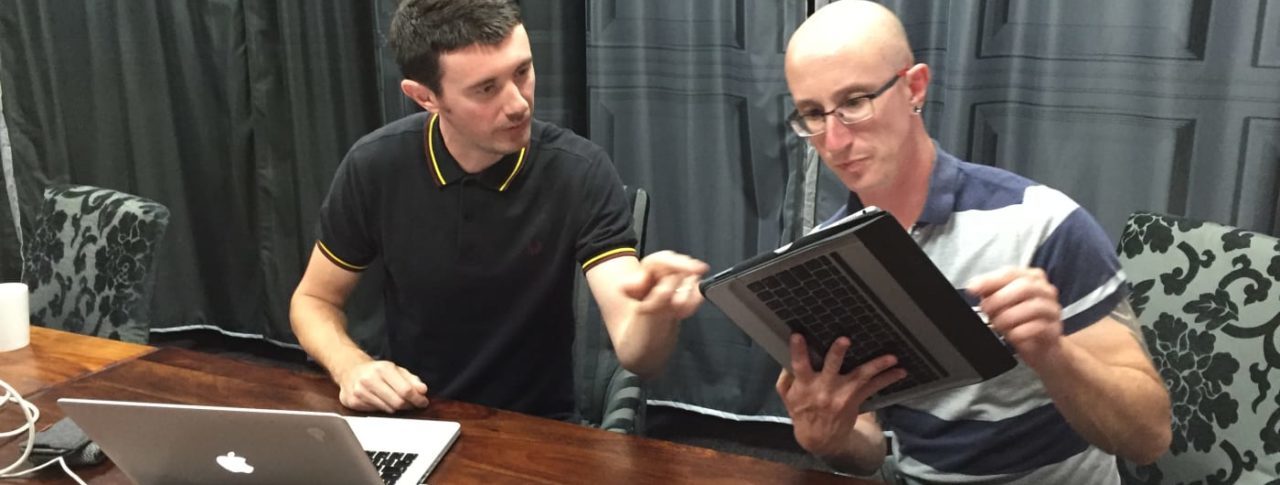 Two men in office interecting with tablet and laptop machines
