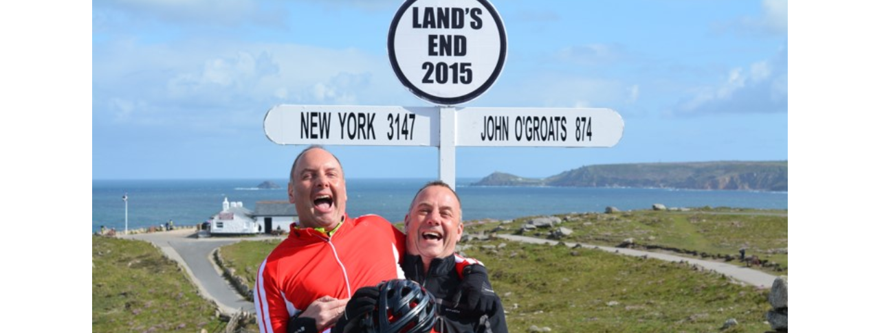 Steve and brother laughing, one carrying the other, they are standing in front of a sign that reads Land's end 2015