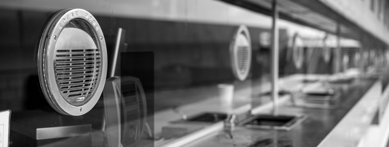 A series of glass fronted ticket officers interspersed with speaking grates.