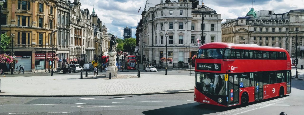 A red London bus, shown going round a roundabout at Trafalgar Square, London.