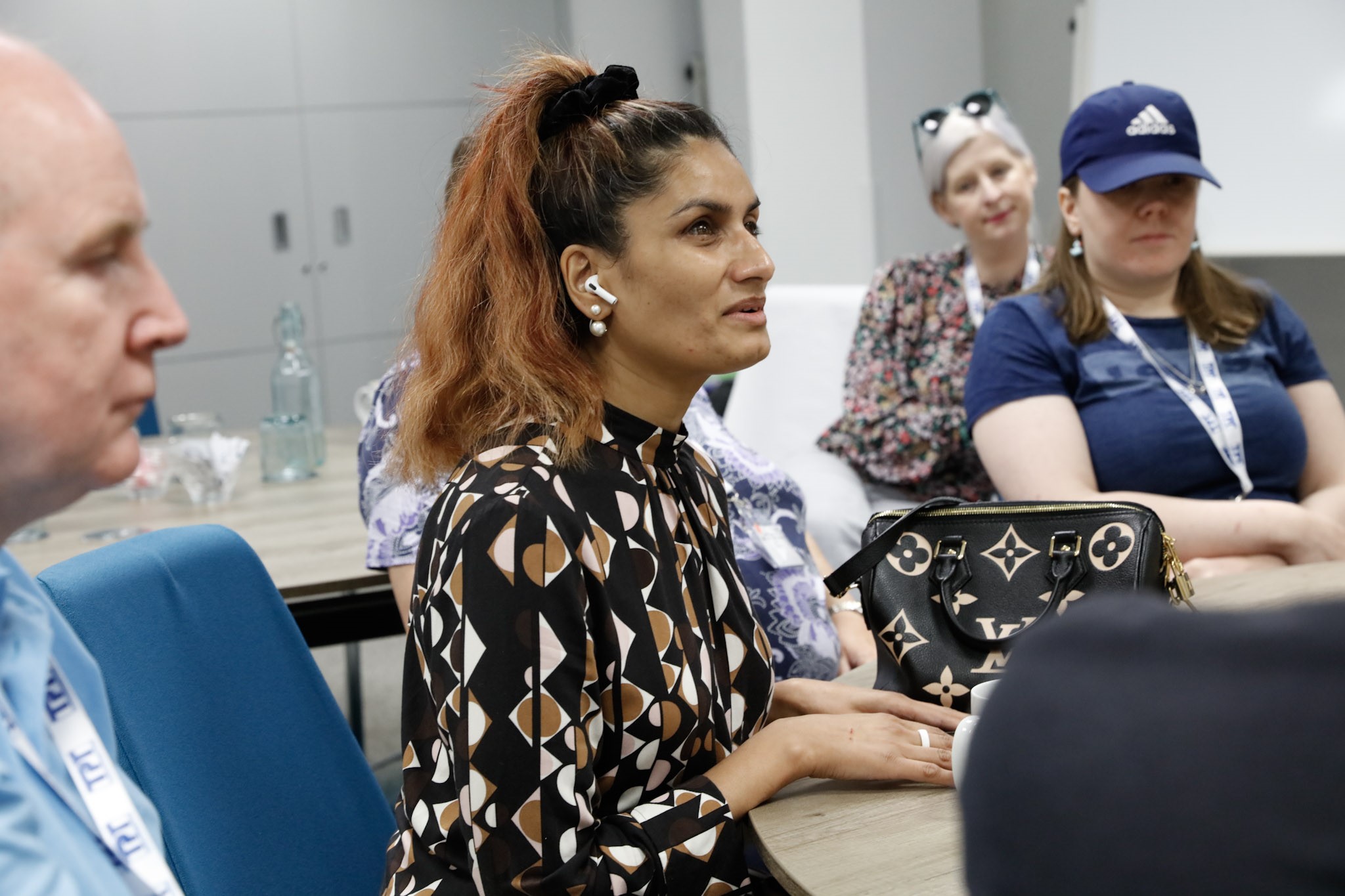 Anela Wood, West of England SLC member, talking during the Health project session at the 2023 SLC conference. She has an air pod in her ear. Other delegates are shown listening to her.