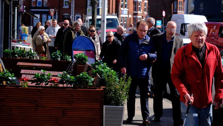 Sefton Council staff members shown during the sim spec walk. They are walking in pairs along a pavement, navigating plant pots and advertising boards.
