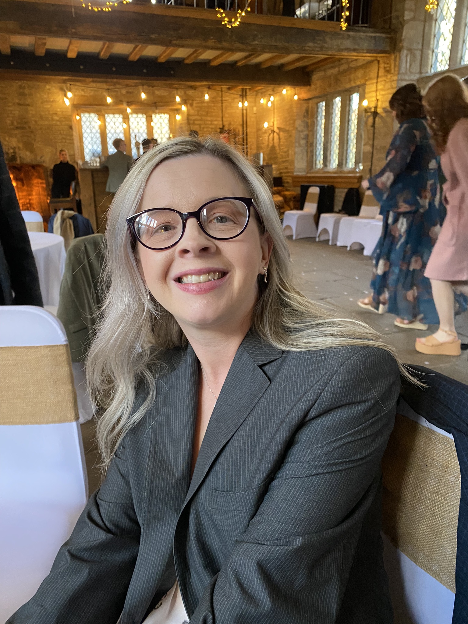 Greater Manchester SLC member, Hayley Kellard. She has long, blonde hair and is wearing glasses. She is seated, smiling at the camera.