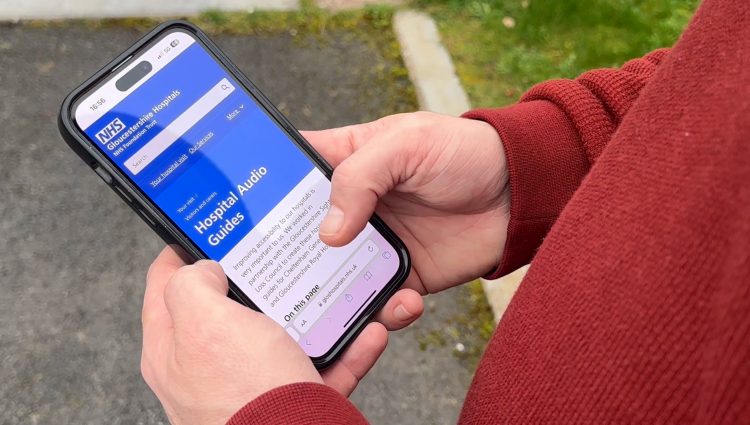 Overhead shot of someone holding their smartphone, viewing the NHS Hospital Audio Guides.