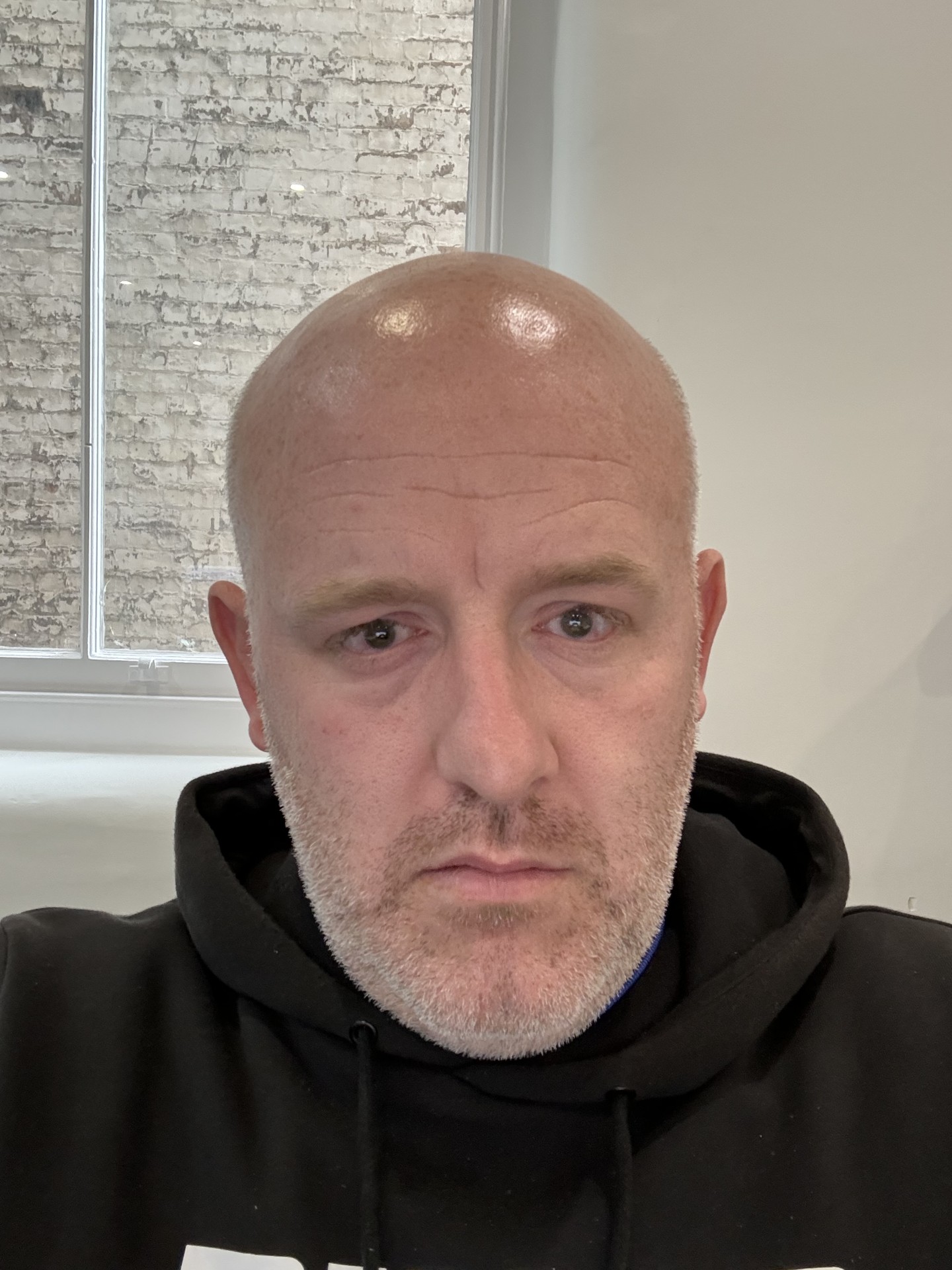 Headshot of Josh Brown, Sussex SLC member. Josh has a shaved head and a short, grey beard. He is wearing a black hoodie and looking at the camera.