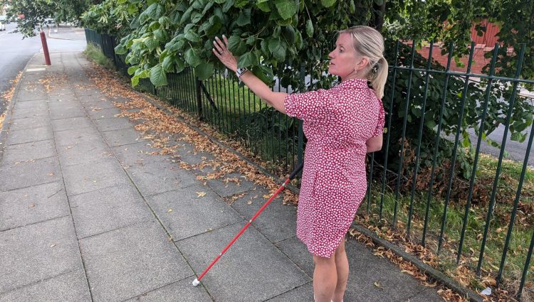 Sight Loss Council Engagement Manager, Kelly, who is registered blind, walks into an overgrown and overhanging tree whilst walking down the pavement.