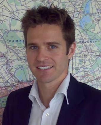 Headshot of Mark Evers, Chief Customer Officer at TfL. Mark is standing in front of a London map and smiling at the camera.