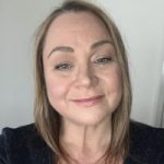 PJ Balderstone headshot. PJ has blonde hair and is wearing a black top. She is smiling at the camera.