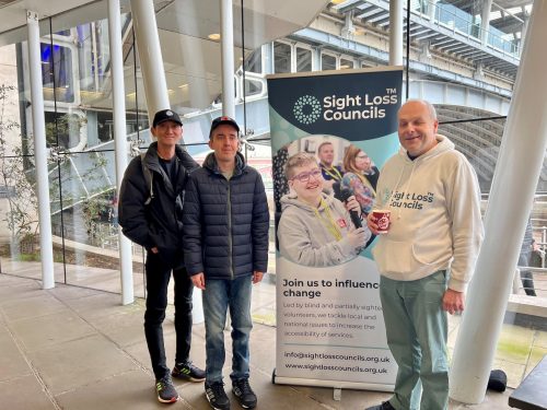 North London SLC volunteers Paul and Jordan standing with Coordinator Liam in front of the SLC banner at Blackfriars station