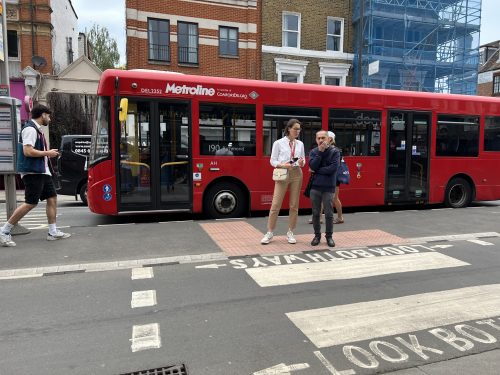 Members of the Planning and Development team are standing in-front of a red London bus on a bus stop. 