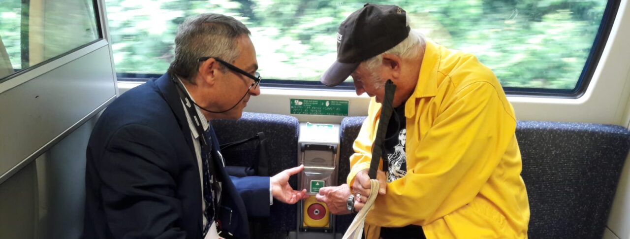 Antony Merlyn, Accessibility Engagement Manager, talking to a VI attendee at London SLCs Try a Train event. Antony is showing and explaining a feature on board the train.