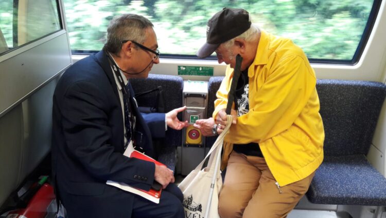 Antony Merlyn, Accessibility Engagement Manager, talking to a VI attendee at London SLCs Try a Train event. Antony is showing and explaining a feature on board the train.