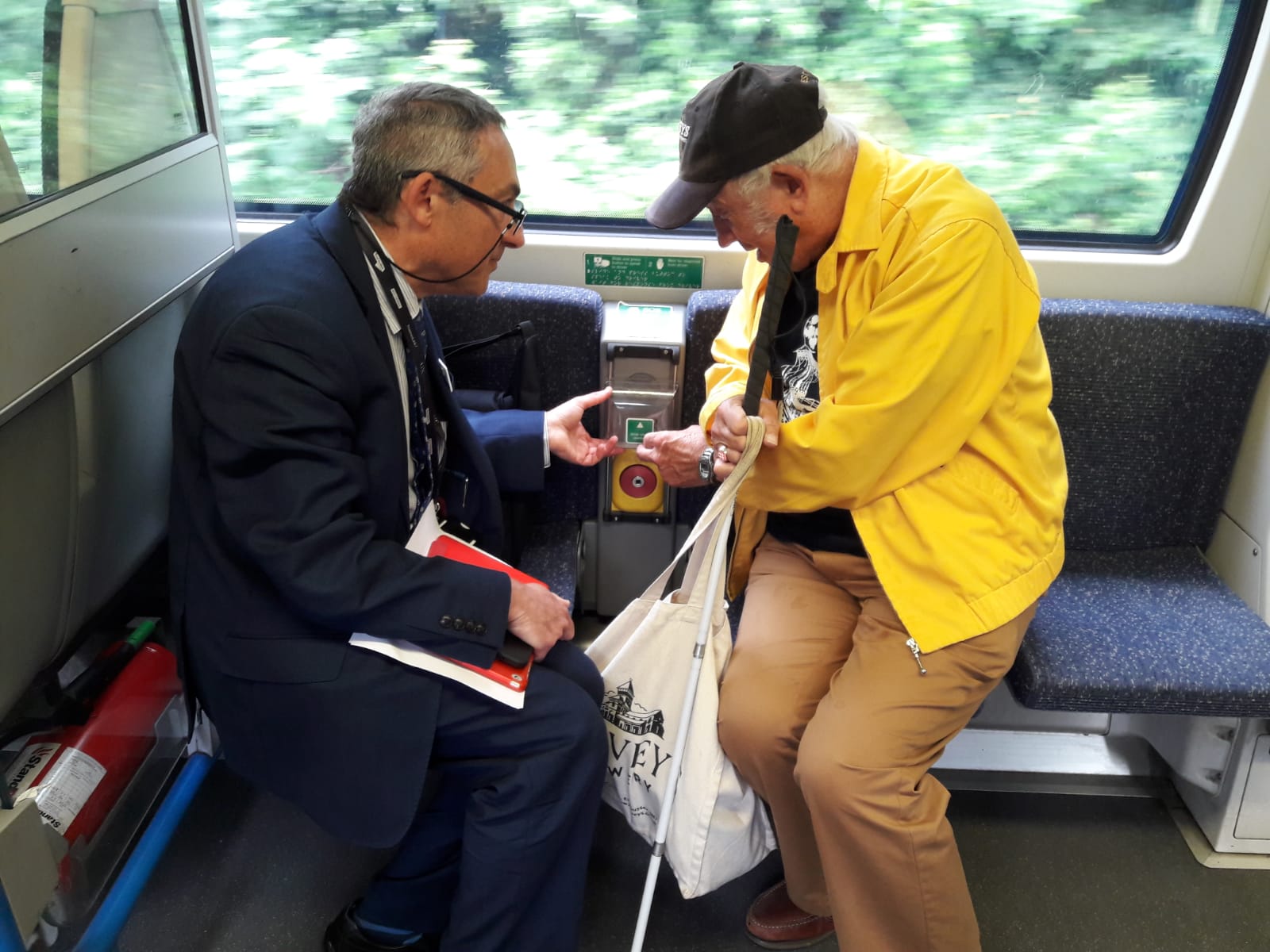Antony Merlyn, Accessibility Engagement Manager, talking to a VI attendee at London SLCs Try a Train event. Antony is showing and explaining a feature on board the train.