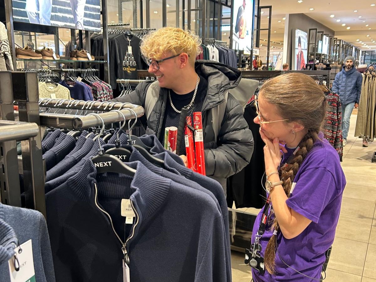 Antony, GM SLC member, is shopping with a female staff member. He is looking at clothes on a clothes rail.