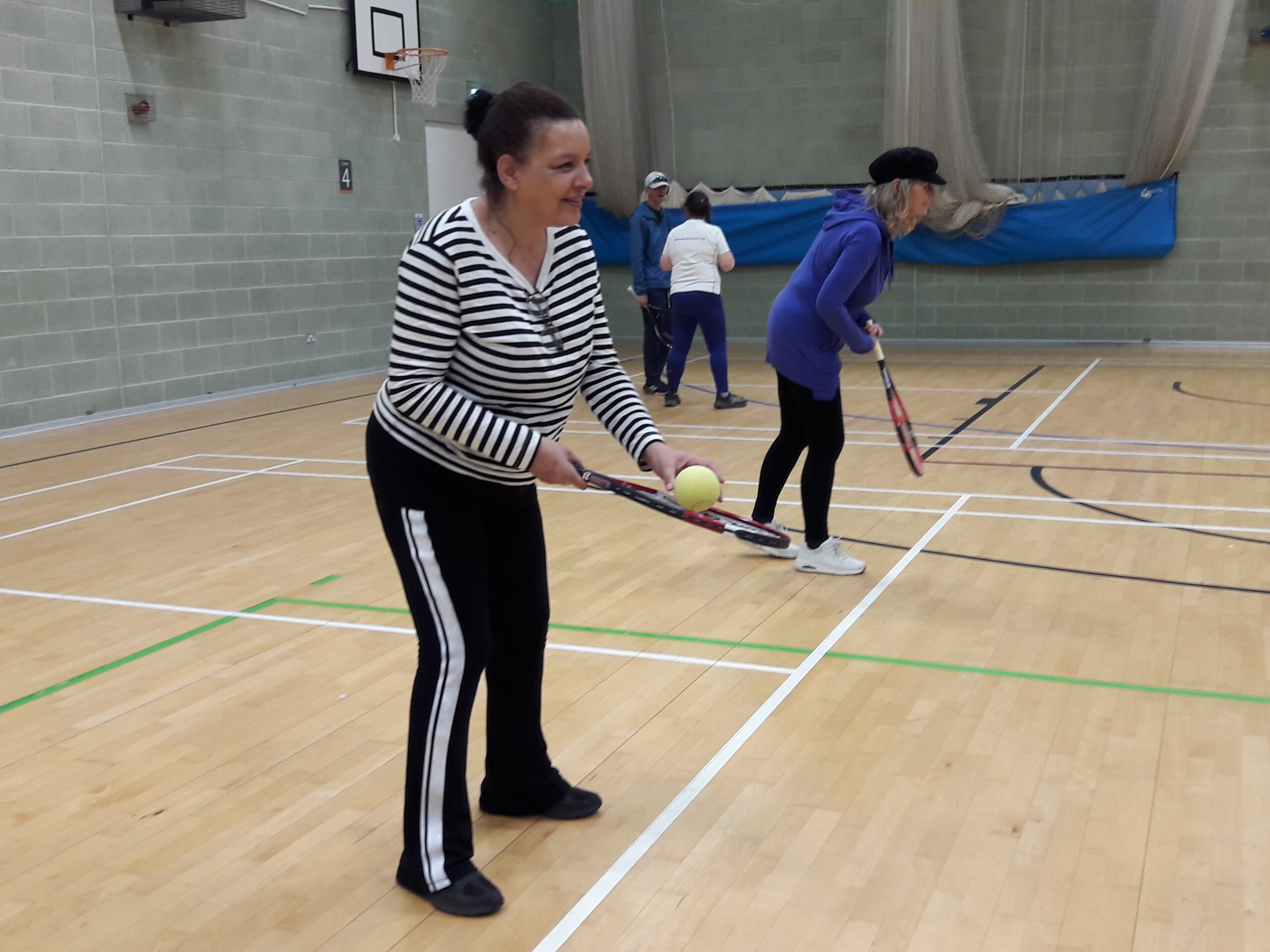 Denise, SE London SLC member, practising bat and ball techniques during the VI Tennis session. Another female participant is beyond her, doing the same.
