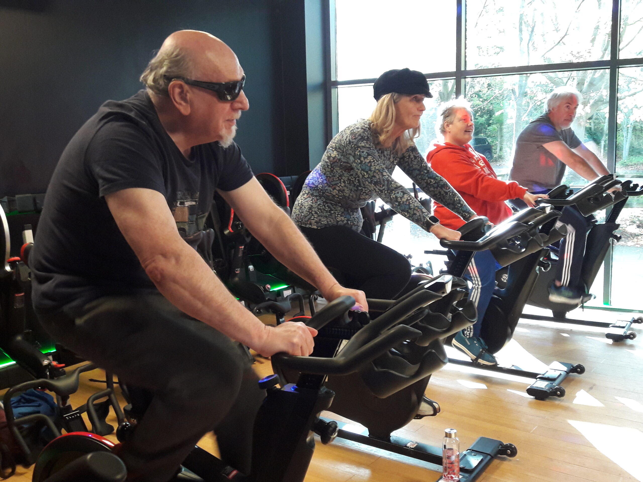 Taken from the side, this image shows four participants on spin bikes during one of the intro to spin session. They're all looking forwards.