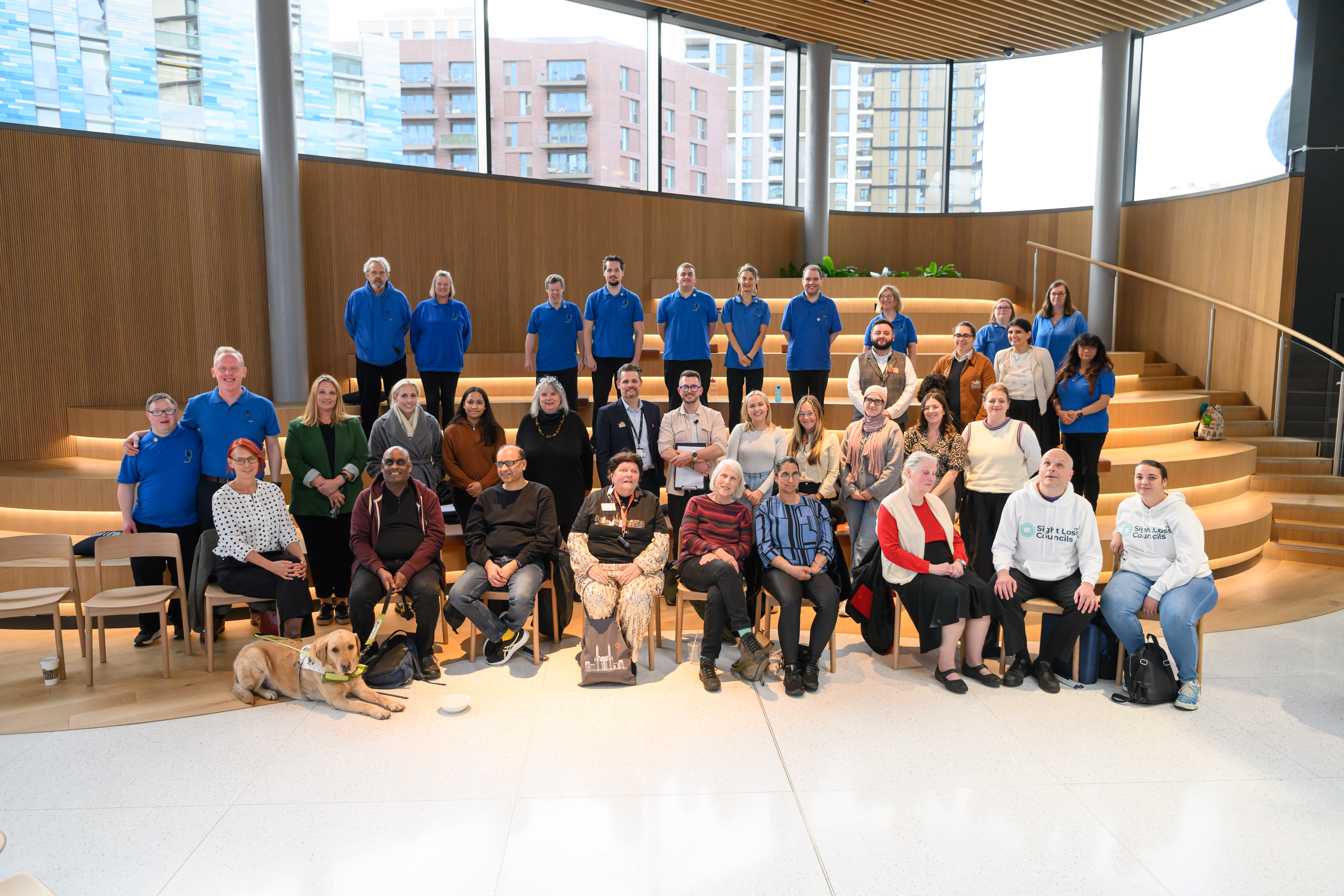A group shot at 50 Electric Boulevard, where the panel discussion took place. Members of London SLC are sat with Down Syndrome UK, TEAM LEWIS, Convo, and Ethos Farm Guest Experience staff