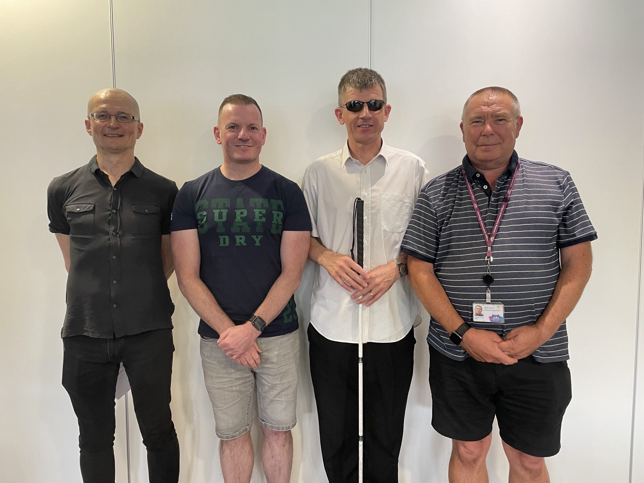 Dave Smith, EM for the South East, standing with three white males against a white wall, who each were guest speakers at the event from various transport organisations in Brighton and Hove.