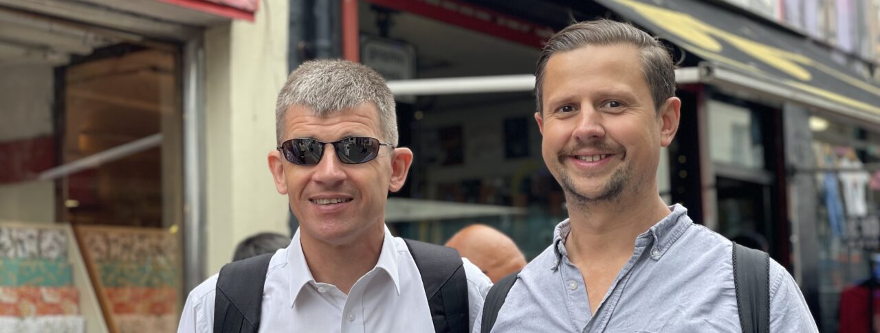Dave Smith, Engagement Manager for the South East, pictured in Brighton with his support worker. Both are smiling at the camera.