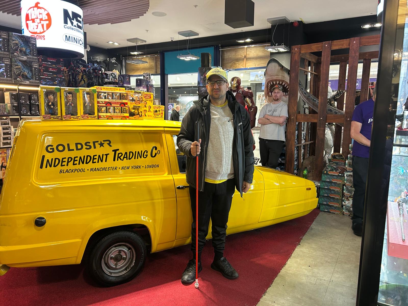 Abubakr,standing next to the Only Fools and Horse Reliant Regal Supervan, in a memorabilia shop.