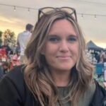 Chloe Hesse, Northumberland and Cumbria Sight Loss Council member, who is sat outside at a festival. She has long, fair, wavy hair and is wearing glasses on top of her head. She is smiling at the camera.