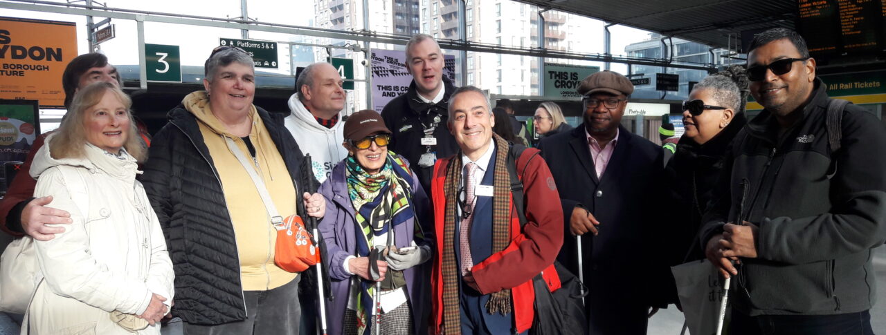 A group shot of everyone standing in the entrance hall at East Croydon station posing for the camera