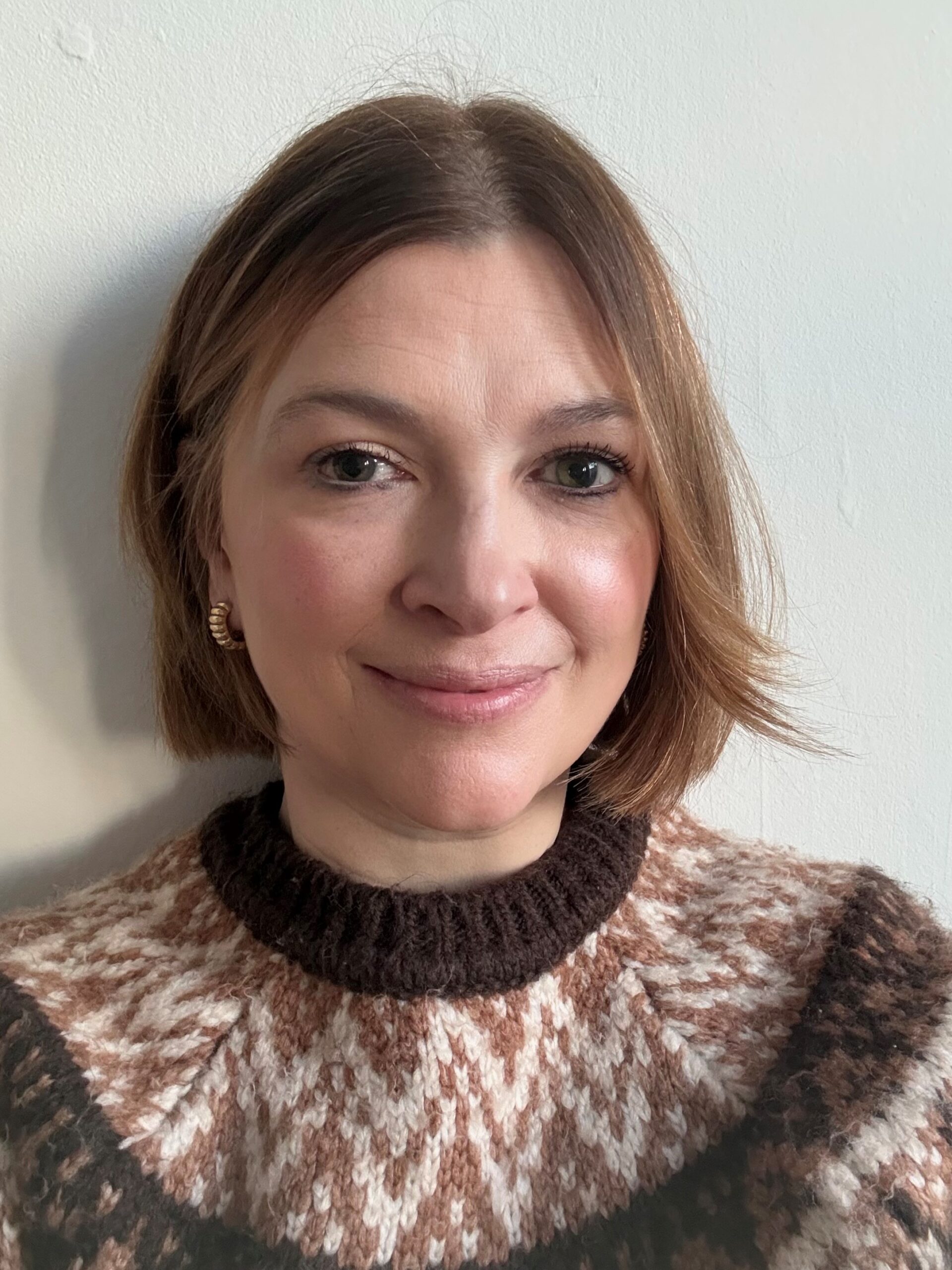 Headshot of Nicki, SLC Communications Officer. She has a short, brown bob and is wearing a chocolate brown, fair isle jumper. She is smiling at the camera.