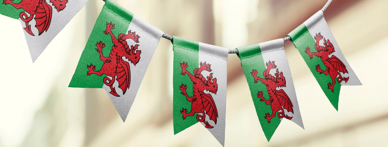 Five Welsh flags hanging from bunting with a blurred street in the background.