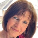 Photo of Joy Drury, Essex SLC member, shown from the shoulders up. She has shoulder-length, dark hair and is wearing a bright pink zip-up jacket.