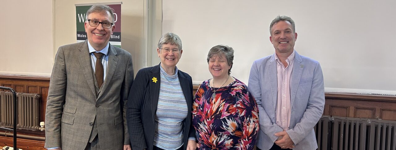 From left to right: Owen Williams, Director of Wales Council of the Blind, Jane Hutt MS, Cabinet Secretary for Social Justice, Anita Davies, Engagement Manager for Wales, and Martin Symcox, Head of Partnerships at Thomas Pocklington Trust. They are stood together in a line, smiling at the camera, during the launch event.