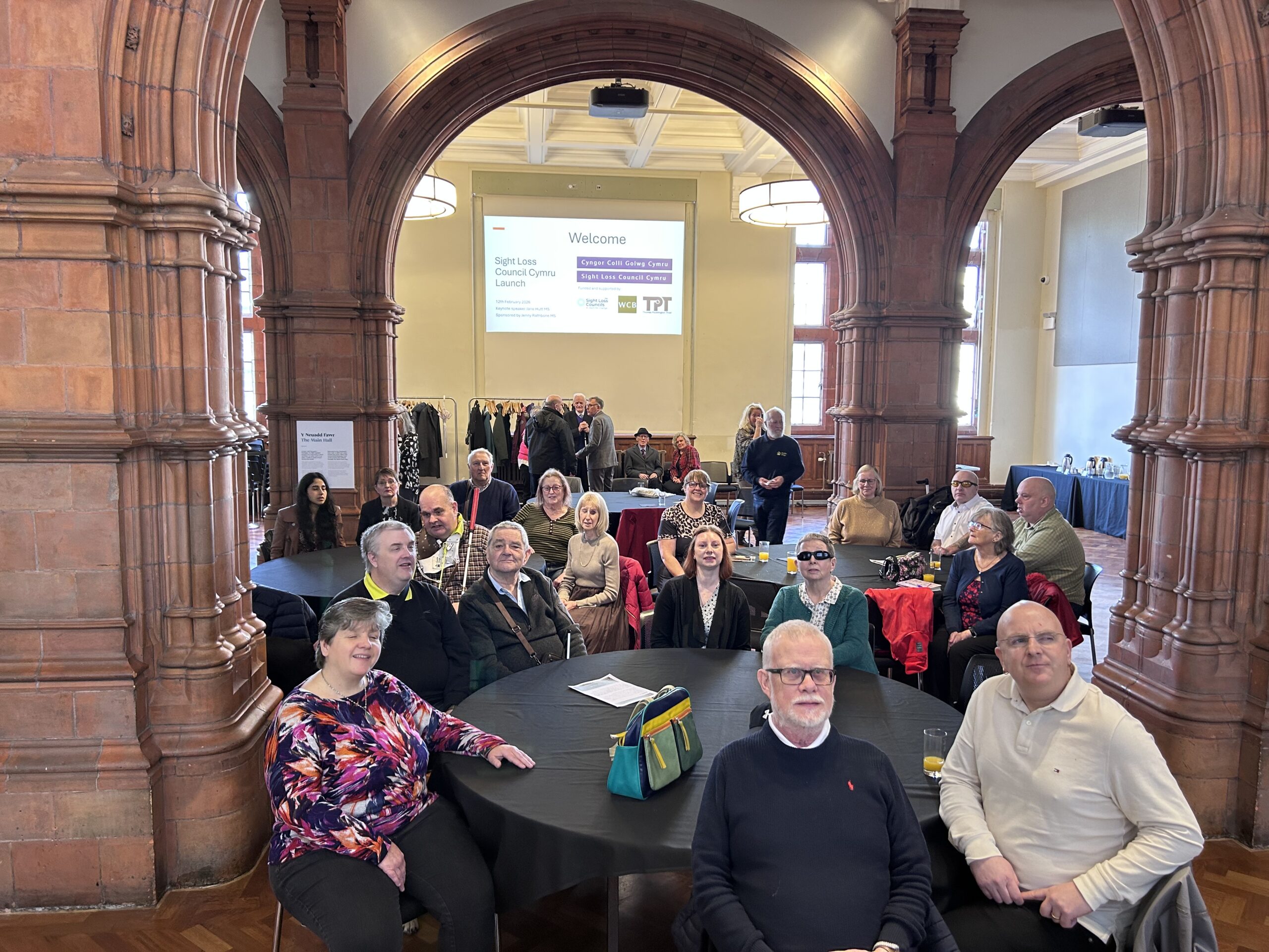 Wales Sight Loss Council members seated around tables in a large hall during the launch event.