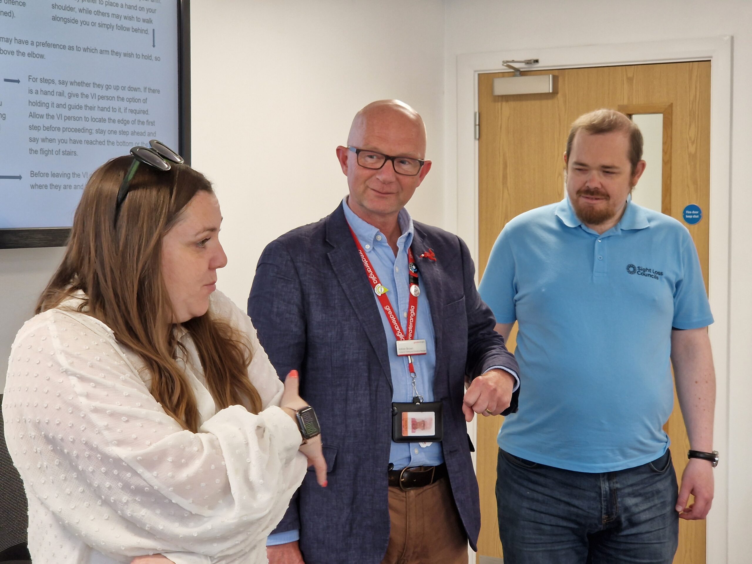 From left to right: Sam, Engagegement Manager for East England, Adrian Brown, Conductor Training & Standards Manager for Greater Anglia, and Lee, Essex SLC member. They're stood at the front of the room - Lee and Adrian look on as Sam speaks to the room.