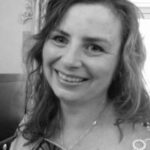 Black and white headshot of Paula, north London SLC member. She has shoulder-length wavy hair, and is facing the camera, smiling.
