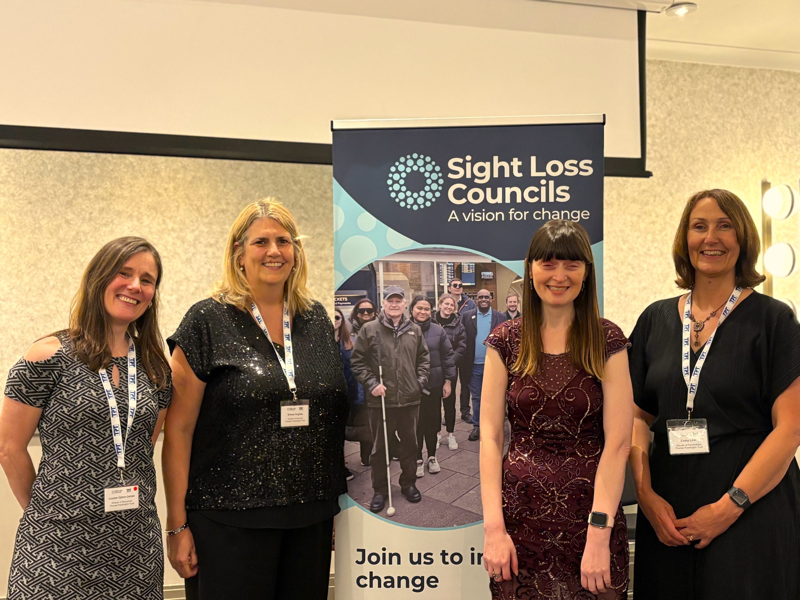 Louise Upton-James, Director of Resources, Emma Hughes, Director of Services, Fern Lulham, Rodney Powell Award host, and Cathy Lowe, Director of Partnerships, stand beside a Sight Loss Councils at the Rodney Powell Awards.