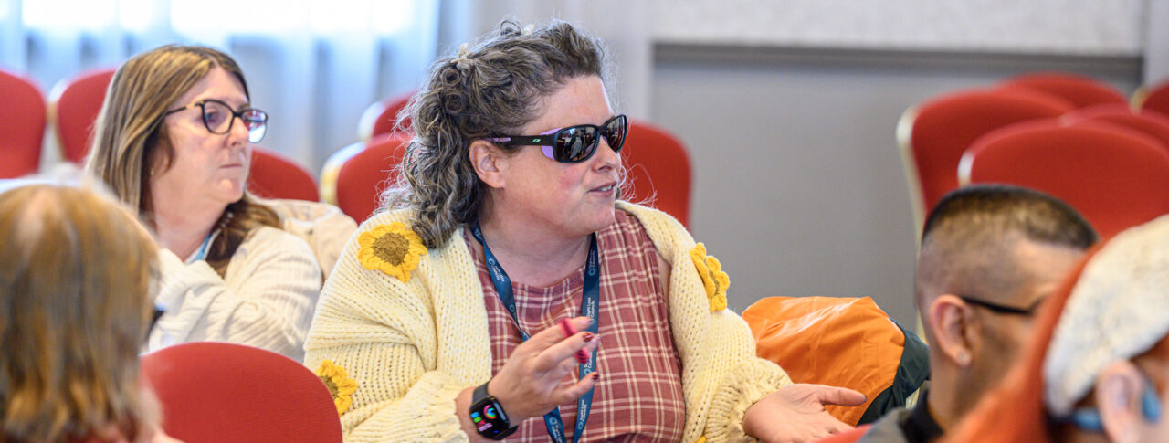 Tyne and Wear Sight Loss Council volunteer Beth, contributing to a discussion during a conference workshop. Other delegates are seated around her.