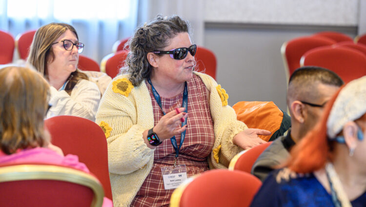 Tyne and Wear Sight Loss Council volunteer Beth, contributing to a discussion during a conference workshop. Other delegates are seated around her.