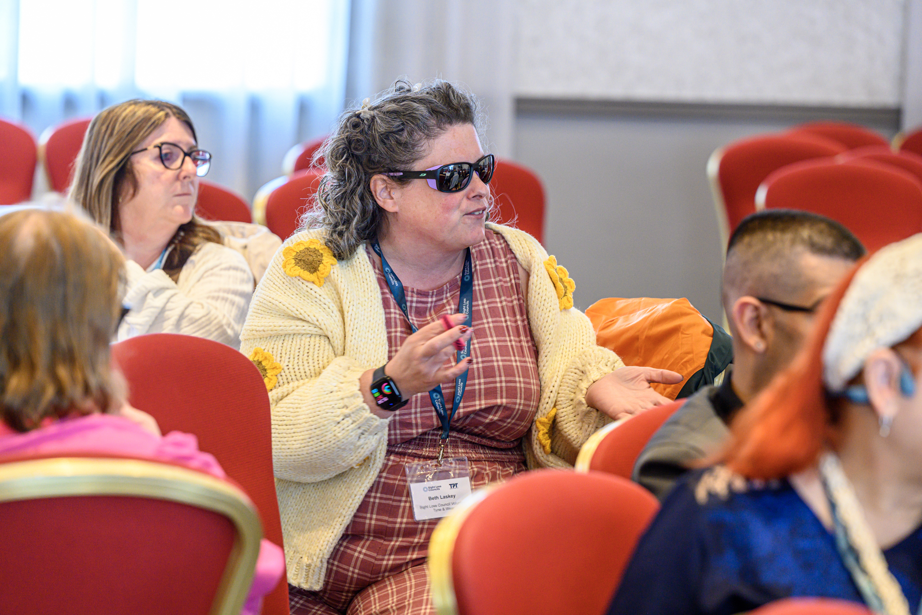 Tyne and Wear Sight Loss Council volunteer Beth, contributing to a discussion during a conference workshop. Other delegates are seated around her.