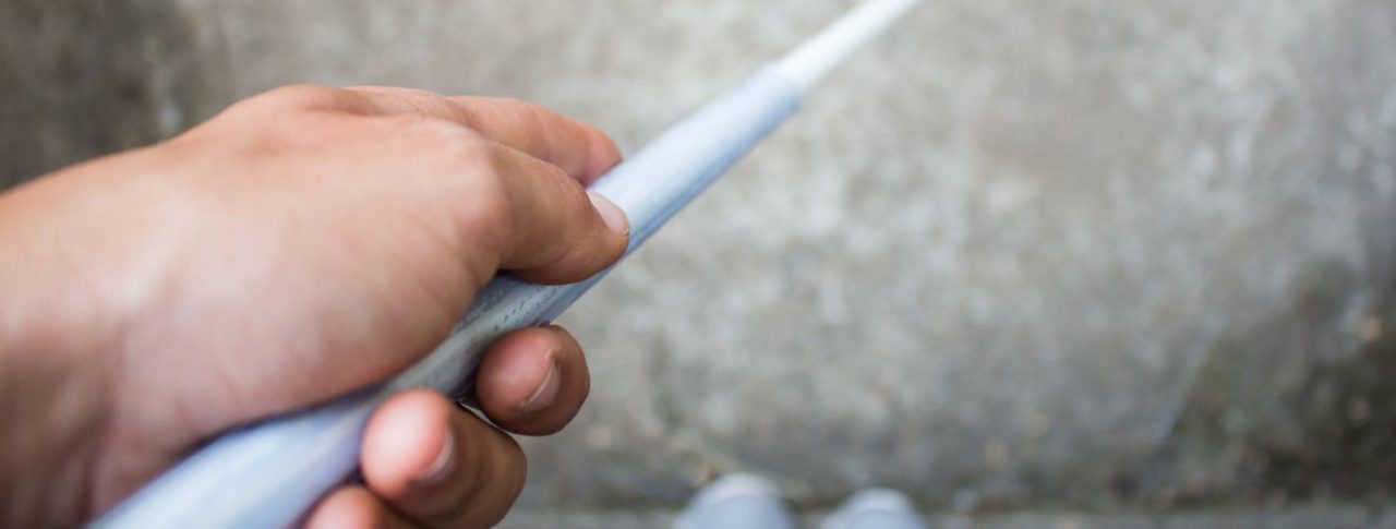 close up of hand holding white cane