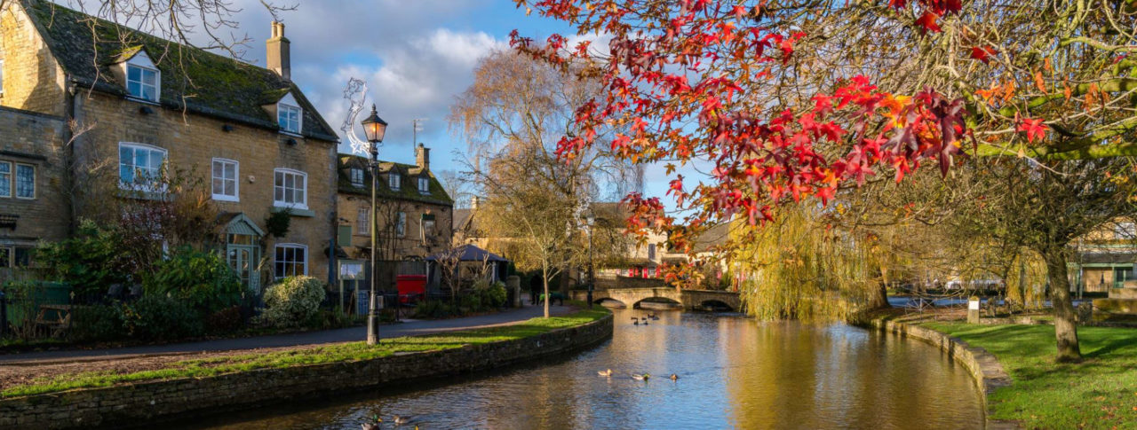 Pretty village shot from Gloucestershire with river next to cottages and trees