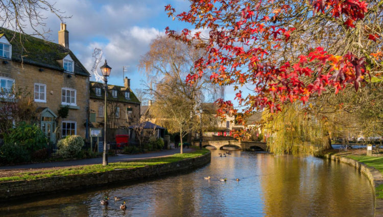 Pretty village shot from Gloucestershire with river next to cottages and trees