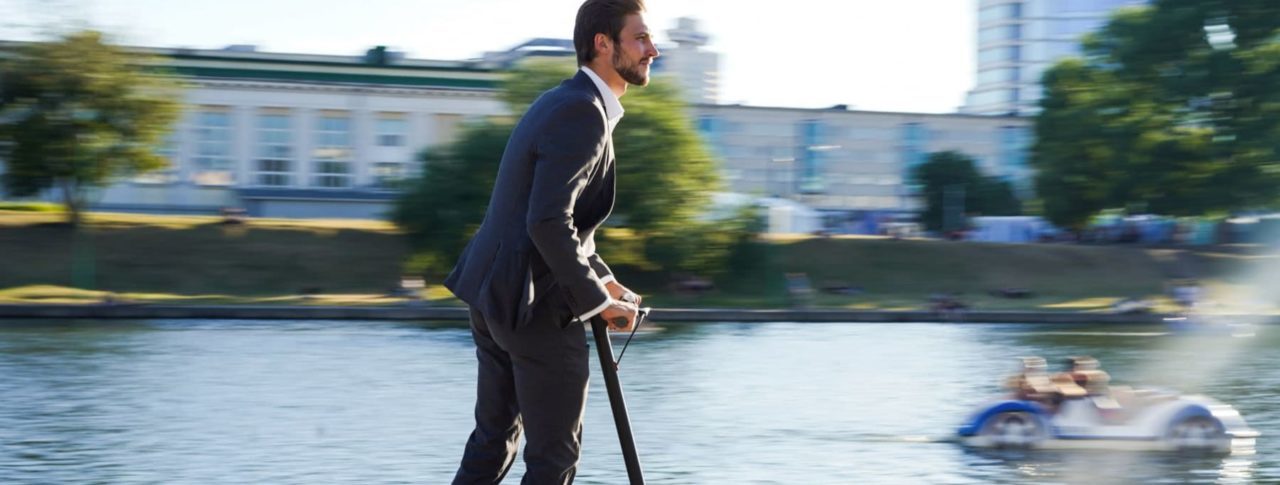 Image showing man on e-scooter next to a river