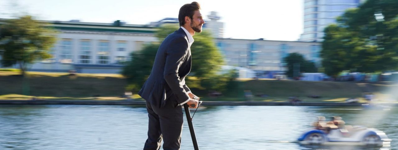 Image showing man on e-scooter next to a river