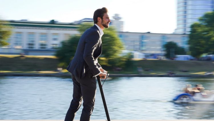 Image showing man on e-scooter next to a river