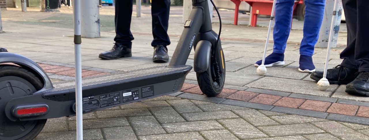 feet and white canes surrounding an e-scooter