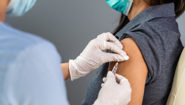 Close up doctor holding syringe and using cotton before make injection to patient in medical mask. Covid-19 or coronavirus vaccine