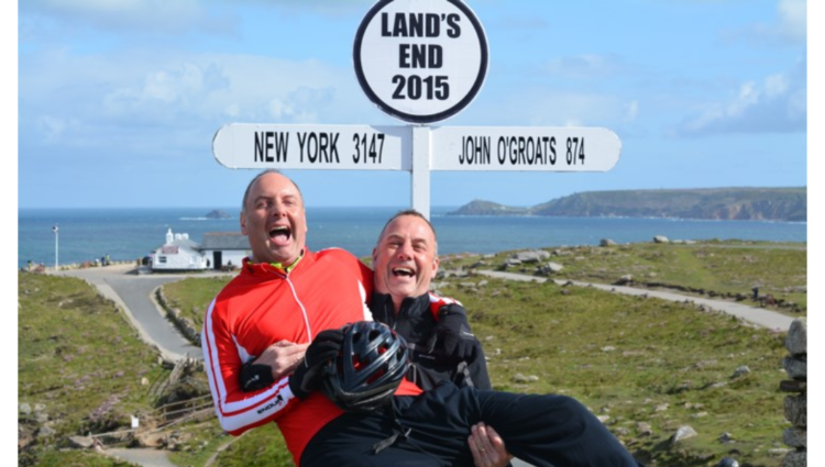 Steve and brother laughing, one carrying the other, they are standing in front of a sign that reads Land's end 2015