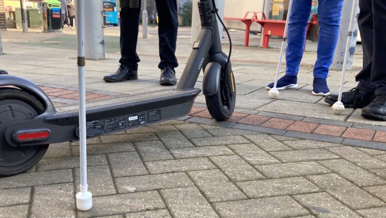 feet and white canes surrounding an e-scooter