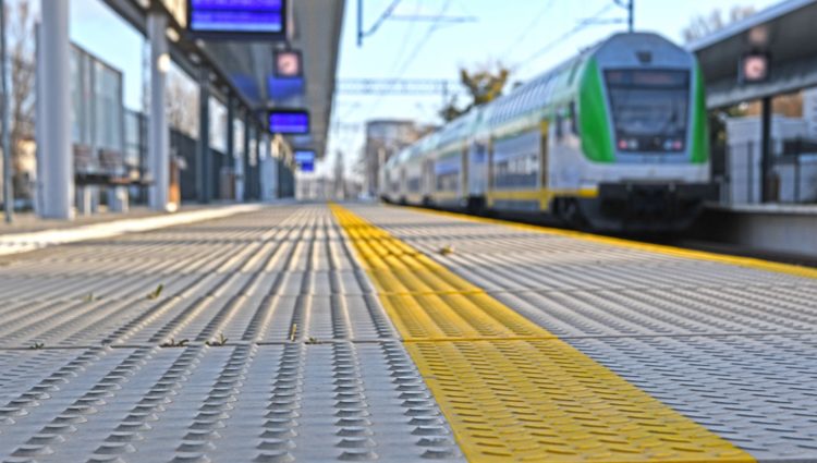 Station platform with tactile paving and a train just approaching