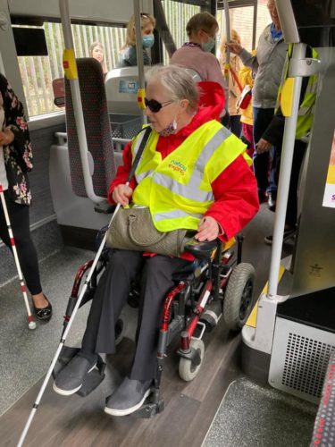 a wheel chair and white cane user aboard a bus