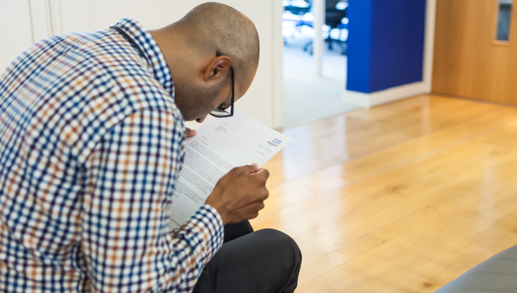 Man wearing glasses struggling to read NHS letter